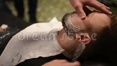 男人在理发店或发廊`发型和理发。 梳胡子。 理发店。 男理发师在做